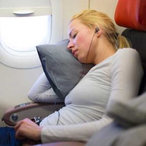 woman sleeping on flight with earbuds